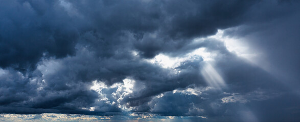 Storm clouds and rays of the sun on a dark background.