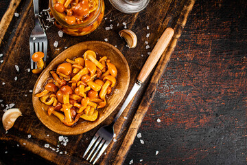Marinated mushrooms on a wooden plate. 