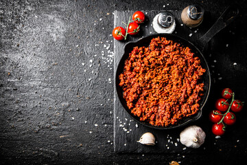 Bolognese sauce on a stone board with spices, garlic and tomatoes. 