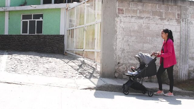 Mujer manejando una carriola con un beb&eacute; en la calle de d&iacute;a video en HD 