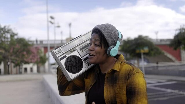 Young African american woman singing urban music outdoor with city on background