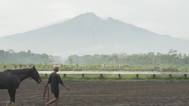 Jockey train their horses at Tegalwaton race track in Semarang regency, Indonesia with mountain background scenery
