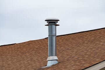 metal chimney on house roof, clean new shiny chimney pipe on blue sky background