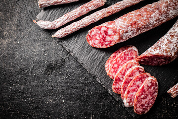 Pieces of salami sausage on a stone board. 