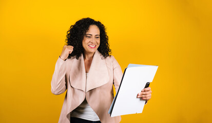 hispanic adult woman portrait holding folders and blank sign on yellow background in Mexico Latin...