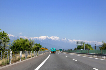 Fototapeta premium 空いてる高速道路と雪山と青空 白馬・北アルプス