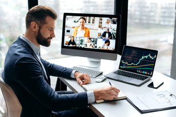 Fototapeta na wymiar Busy clever focused caucasian executive, stock investor, sits at a desk in office, talking on a video conference with his partners, discussing risks, ideas, strategy, takes notes, listens information