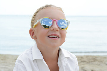 Little girl wearing sunglasses at beach on sunny day