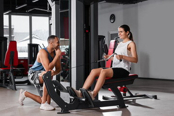 Fototapeta na wymiar Happy trainer cheering up woman while she doing exercise in modern gym
