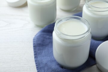 Tasty yogurt in glass jars on white wooden table, closeup. Space for text