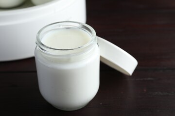 Glass jar with tasty yogurt on wooden table, closeup
