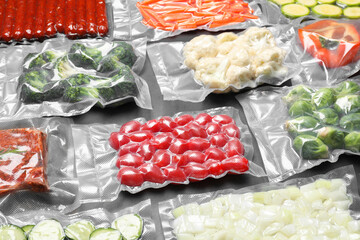 Many different food in vacuum packings on dark grey table, closeup