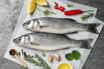 Sea bass fish and ingredients on grey table, top view