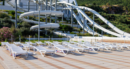 Empty water park with high white slides and white sun loungers