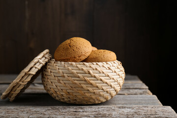 Wicker basket with delicious oatmeal cookies on wooden table