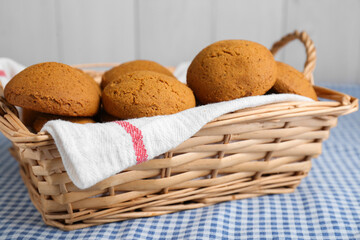 Wicker basket with tasty oatmeal cookies on checkered cloth