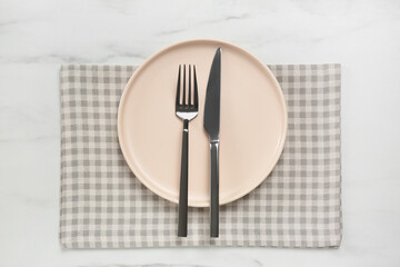 Clean plate with shiny silver cutlery on white marble table, flat lay
