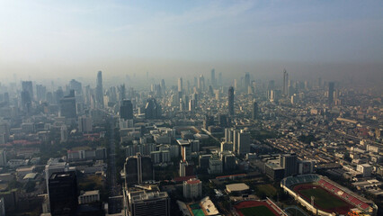 Aerial drone view of a thick layer of air pollution and dust covering the city during morning time...