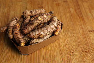 Fototapeta premium Cardboard box with whole turmeric roots on wooden table. Space for text