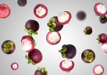 Many ripe mangosteen fruits falling on light grey background