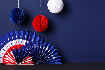 Paper fans in the colors of the American flag and balls decorations on dark blue background. USA Presidents Day, Independence Day, American Labor day, Memorial Day, US election concept.