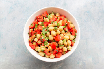 Healthy food chickpeas salad add tomato coriander in white bowl on blue wood background.