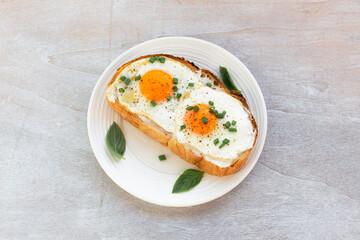 Breakfast food fried egg on bread slice in plate on white wood table