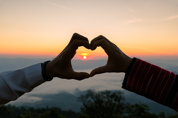 Silhouette of wedding Couple in love hand sign heart during sunrise with morning sky background....