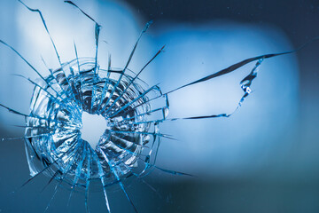 Bullet holes in the glass on the background of the blue sky.