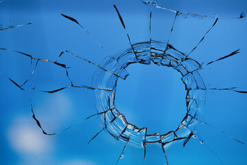 Bullet holes in the glass on the background of the blue sky.