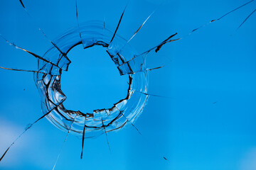 Bullet holes in the glass on the background of the blue sky.