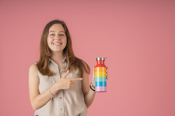 Smiling young woman pointing to her rainbow bottle