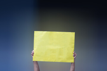 Mão segurando cartaz amarelo