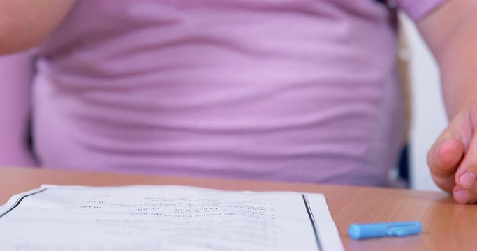 The bully took apart a plastic ballpoint pen, stuffed a wad of paper inside to shoot someone with it during the lesson, close up, front view. School bullying. Friendly prank. 