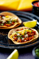 Delicious lunch with tacos and sauces on black table of appetizing Mexican tacos served on black plate near bowl with tomato sauce and avocado placed on wooden table