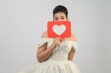 Asian beautiful bride smiling and posing with heart sign on white background