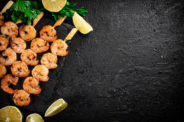 Grilled shrimp on a stone board with parsley and lime.