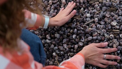 Lots of shells on the river bank. Woman picking up small river shells