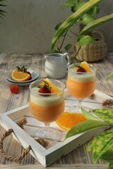 two orange puddings in glasses garnished with sliced ​​oranges and strawberries