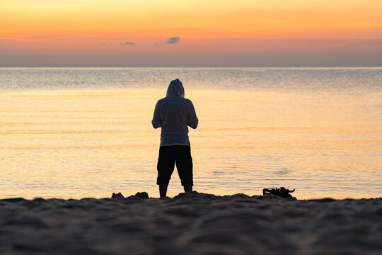 Silhouette of the man standing alone by the sea at colorful dawn