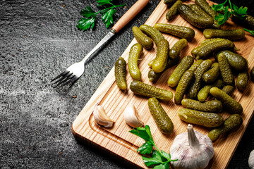 Pickles on a cutting board with garlic and parsley. 