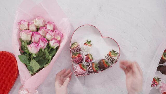 Flat lay. Step by step. Bouquet of pink roses with a box of chocolate dipped strawberries.