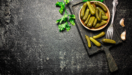 Wooden plate with pickles. On a black background.