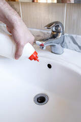 Removal of blockage in the sink, the hand of a man with a bottle of a special remedy with granules....