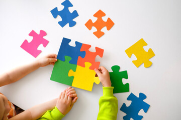 A large puzzle of colorful parts in the hands of a child.
