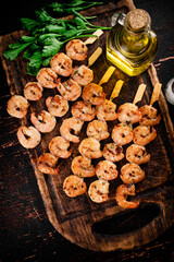 Grilled shrimp on skewers with parsley on a cutting board. 