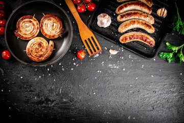 Delicious grilled sausages in a frying pan with fresh tomatoes. 