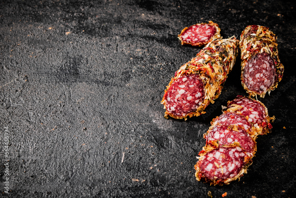 Poster sliced salami sausage. on a black background.