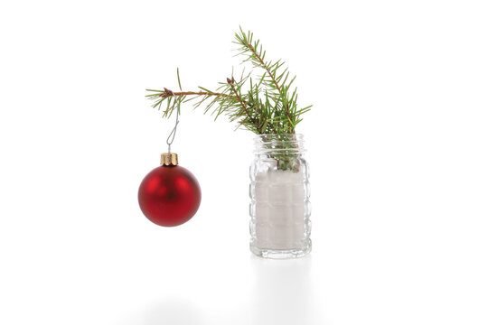 Small pine sprig Christmas tree with red ornament in a salt shaker on a white background