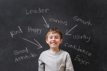 Positive encouraging words written on a blackboard with a happy smiling child © soupstock